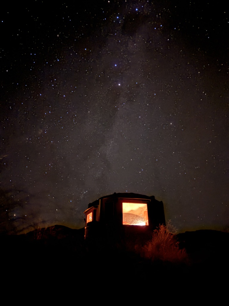 A warmly lit backcountry hut beneath the stars